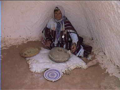 Old woman grinding flour inside an underground house