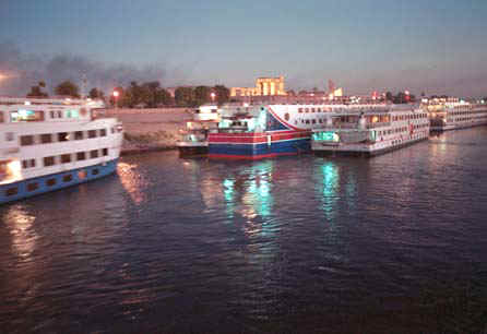 Boats on the Nile at Kom Ombo at night. You can see the monuments lit up at top center