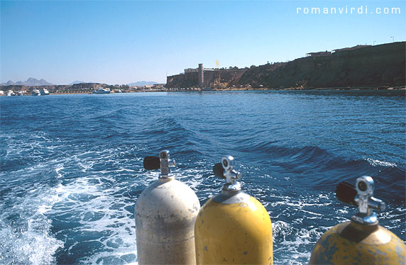 Setting off on a dive boat from Sharm el Sheikh harbour. You can 
see the tower-live elevator structure of the luxury hotel there (it used
 to be the Sheraton Residence, but has since changed hands). This 
picture was taken in 1996, when all dive boats left from here. Today, 
most boats conveniently leave directly from Naama Bay harbour, where 
most of the hotels are located