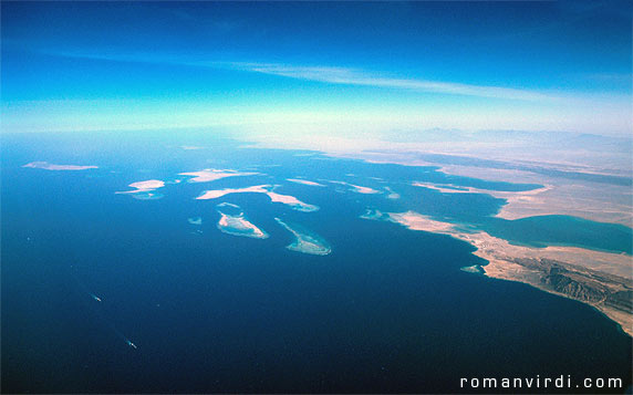 Gulf of Suez: These are the Straits of Gubal from the air. The longish island at the extreme left (a bit unclear) is Shadwan Island. The two (more clearer)  larger islands to it's right are Gubal Island (left) and Tawila Island (right). There are numerous riffs in between Shadwan and Gubal/Tawila which are home to the wrecks of the Chrisoula K., The Giannis D. and the Carnatic, amongst others. Hurghada lies in the mist on the horizon (center leftish)