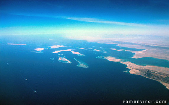 Gulf of Suez: These are the Straits of Gubal from the air. The 
longish island at the extreme left (a bit unclear) is Shadwan Island. 
The two (more clearer)  larger islands to it's right are Gubal Island 
(left) and Tawila Island (right). There are numerous riffs in between 
Shadwan and Gubal/Tawila which are home to the wrecks of the Chrisoula 
K., The Giannis D. and the Carnatic, amongst others. Hurghada lies in 
the mist on the horizon (center leftish)