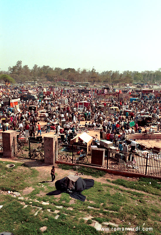Looking out at the market crowd on one side of Red Fort. In the foreground (in black) is a levitator in the process of "floating on air", you can see his head above the black sheets