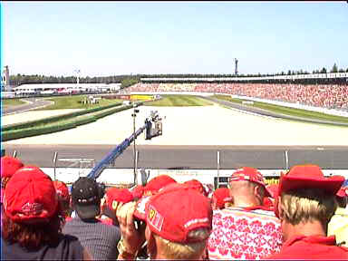 It's quiet and tense just before the start of the main race. Most people are wearing Ferrari Red. The view is on to the loop of the Sachskurve