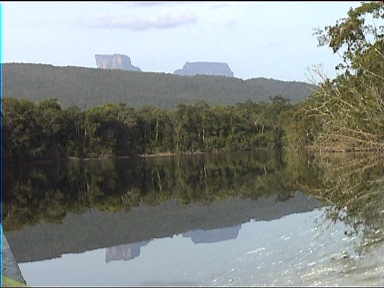 Tepuis in the distance reflect in the water. Water splashing on the right is from our boat