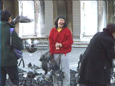 Japanese tourist with bird food in her hand besieged by pigeons
